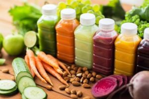 rôzne šťavy z ovocia a zeleniny na detoxikáciu tela, v popredí mandle a zelenina
