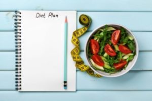 Dietný plán, ceruzka, meter a zelenina v miske
