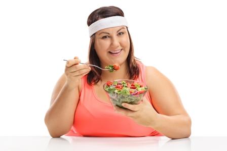 žena drží diétu, sedí pri stole a je šalát